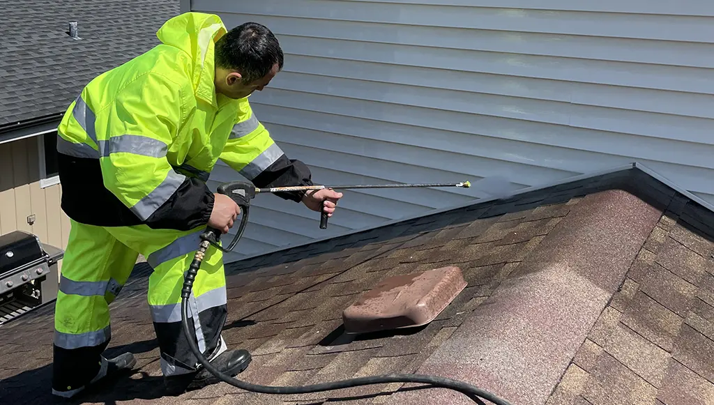 man on the roof washing siding