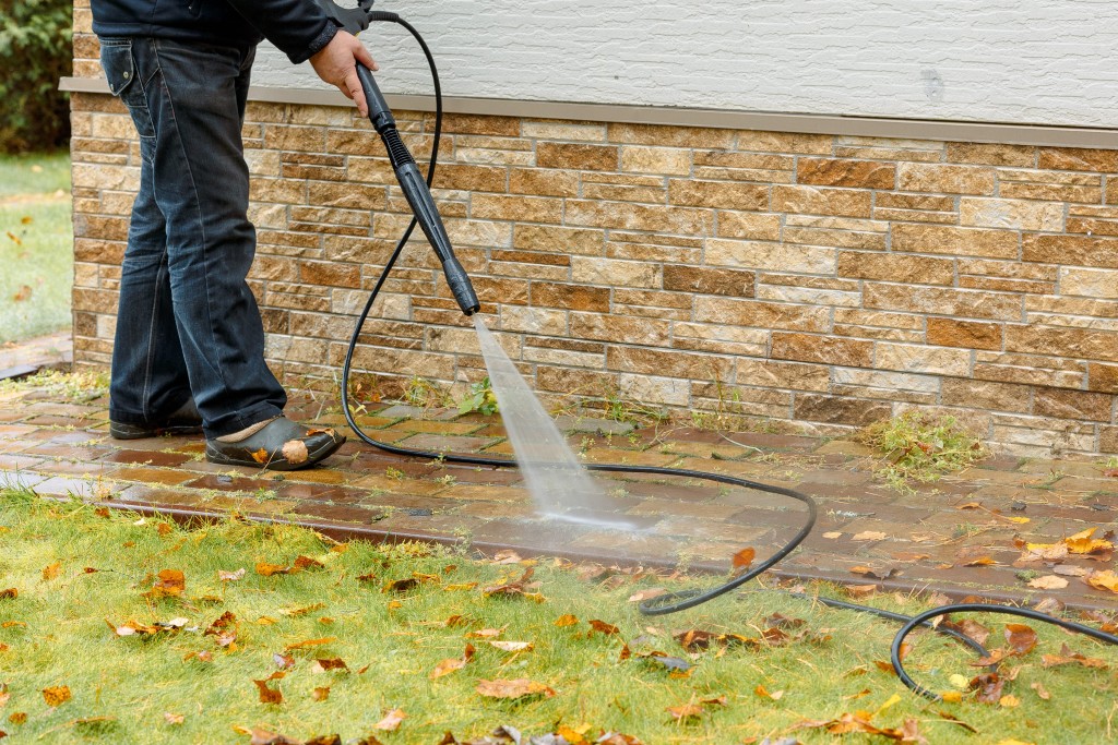 man cleaning path around the house